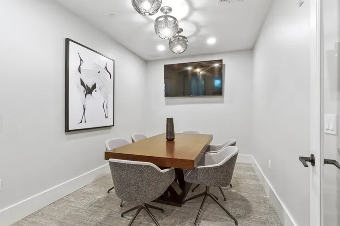 Large business center equipped with a conference room style arrangement and a wall-mounted TV at Lantower Grande Flats Apartments.