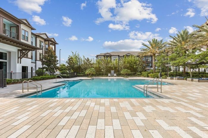 Resort-like pool with palm trees and a sundeck at Lantower Grande Flats Apartments.