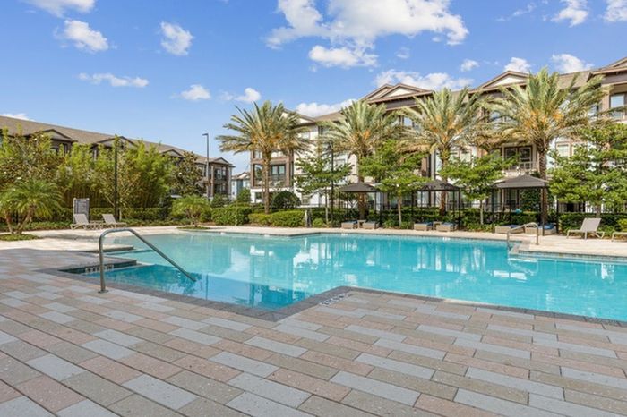 Resort-like pool with palm trees, a sundeck, and private cabanas at Lantower Grande Flats Apartments