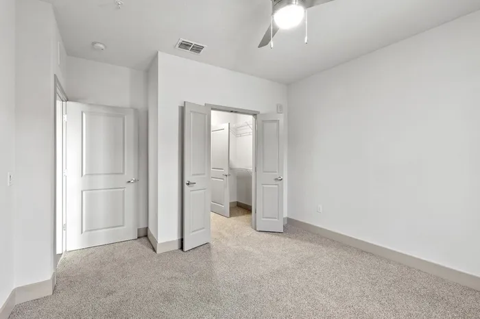 Carpeted bedroom with lots of light and French doors leading to a closet at Lantower Grande Flats.