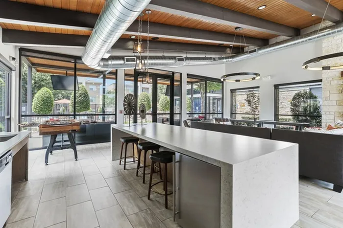 Lounge area with stool seating, stainless steel mini fridge, kitchen, sofas, and ambient lighting at Lantower Legacy Lakes