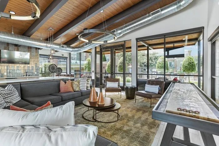 Lounge area with wood-style shuffleboard, gaming area, stone island equipped with stools, sofas, leather seats, and natural lighting at Lantower Legacy Lakes