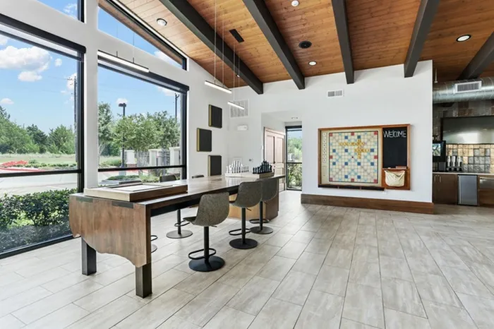 Lounge area with wood-style table, gaming area, chess board, and natural lighting at Lantower Legacy Lakes