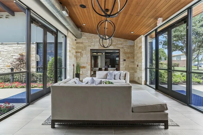 Lounge area with sofas, tile floorings, gaming area and natural lighting provided by glass window walkway at Lantower Legacy Lakes