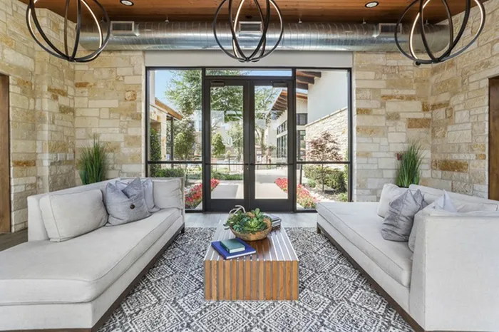 Lounge area with sofas, tile floorings, gaming area and natural lighting provided by glass window walkway at Lantower Legacy Lakes