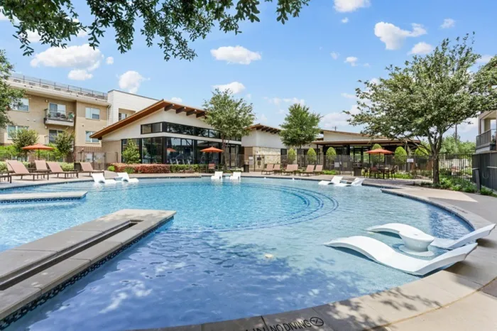 Circular pool equipped with Laid back pool chairs in shallow end of swimming pool facing the deep end of the swimming pool surrounded by Lantower Legacy lakes’ buildings