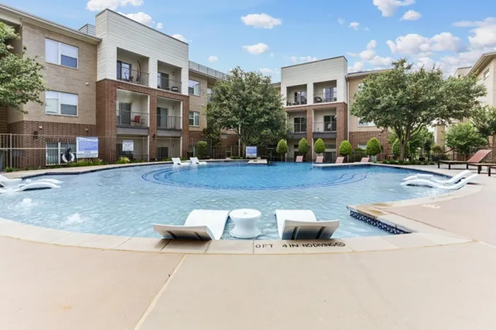 Laid back pool chairs in shallow end of swimming pool facing the deep end of the swimming pool surrounded by Lantower Legacy lakes’ buildings