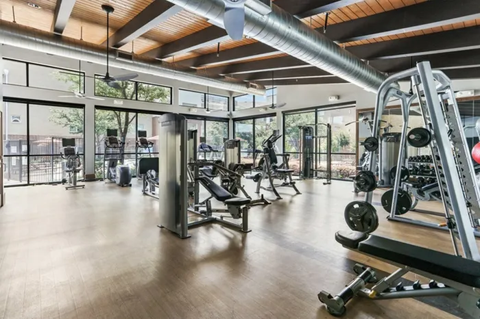 Spacious wood-style flooring with spaced out gym equipment, and surrounded by windows at Lantower Legacy Lakes
