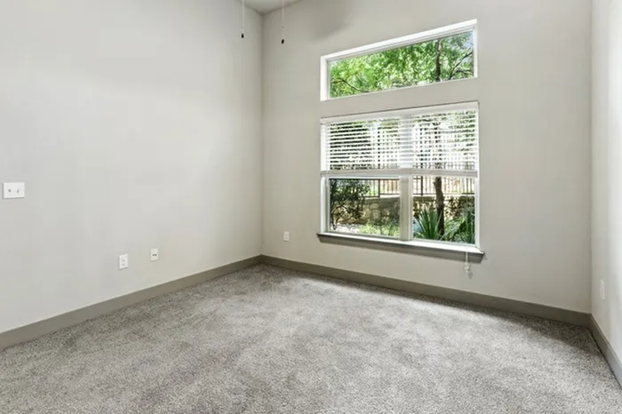 Bedroom with carpet flooring, and large square window providing natural light at Lantower Legacy Lakes