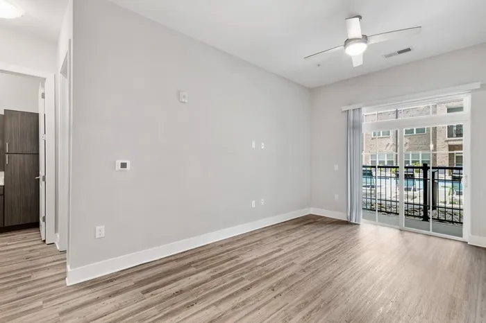 Spacious living room with a ceiling fan, wood-style floors, and a sliding glass door to a balcony at Lantower Weston Corners.