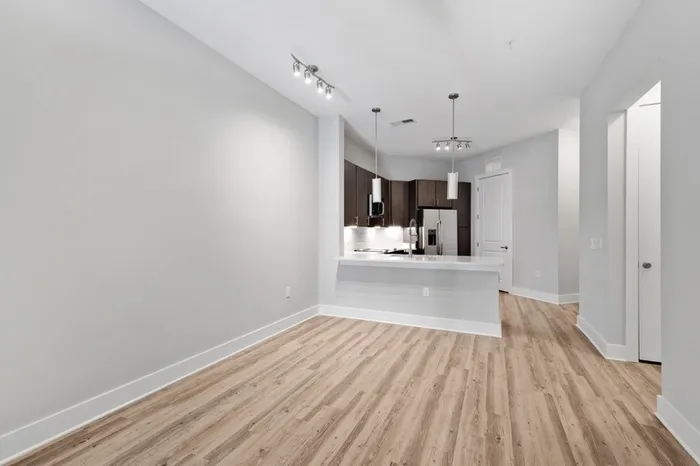 Energy-efficient kitchen with a side-by-side refrigerator, quartz countertops, stainless steel appliances, and a kitchen bar with the wood-style floor living room in the foreground of the image at Lantower Weston Corners.