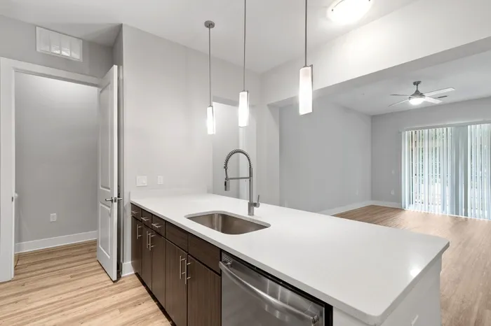 Kitchen with quartz counters, wood-style flooring, dark-colored cabinetry, stainless steel, energy efficient appliances, and tile backsplash at Lantower Weston Corners.