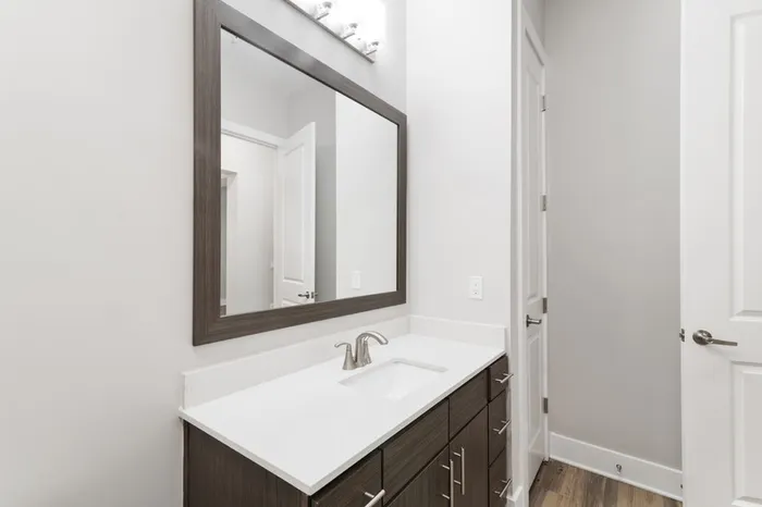 Modern bathroom with dark-colored cabinetry, quartz countertops, 10 foot ceilings, and silver hardware at Lantower Weston Corners.