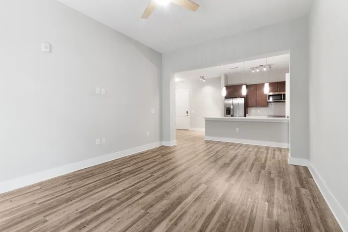 Energy-efficient kitchen with a side-by-side refrigerator, quartz countertops, stainless steel appliances, and a kitchen bar with the wood-style floor living room in the foreground of the image at Lantower Weston Corners.
