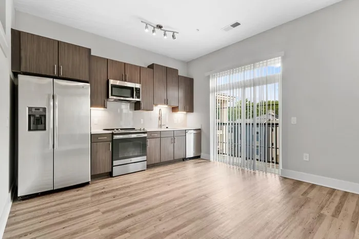 Kitchen with quartz counters, wood-style flooring, dark-colored cabinetry, stainless steel, energy efficient appliances, and tile backsplash at Lantower Weston Corners.