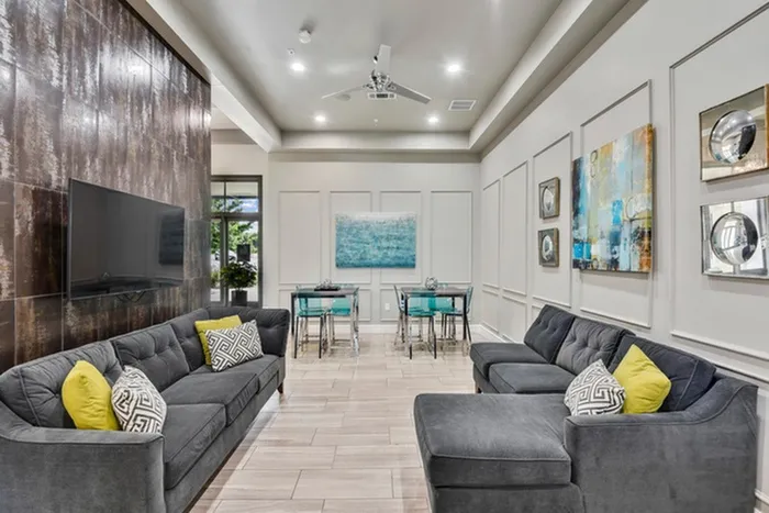 Modern lounging area with a wall mounted TV, cozy sofas, and dining tables at Lantower Techridge