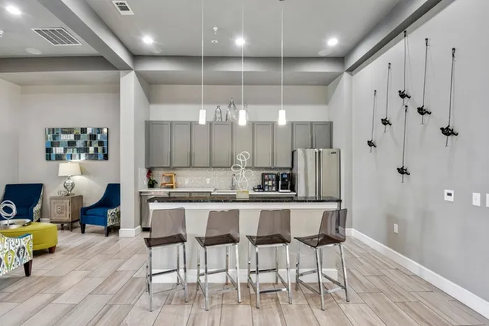 Modern kitchen fit with Bianco Blanco granite kitchens & baths with under mount sinks, Stainless steel appliances, and an island with overhead lighting and modern stools at Lantower Techridge apartments