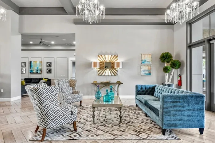 Lounging area with beautiful chandeliers, cozy dark blue sofa, and patterned chairs surrounding a vintage coffee table at Lantower Techridge