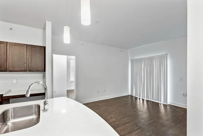 Modern kitchen fit with diamond white quartz countertops and stainless steel sink basin, stainless steel appliances, and an island with overhead lighting, sitting on vinyl plank flooring at Lantower Techridge apartments