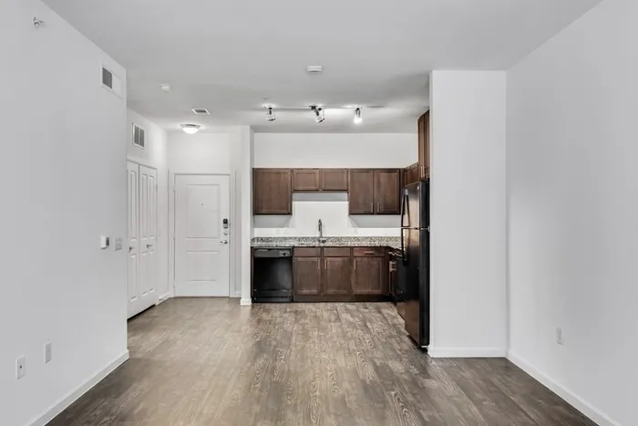 Open and spacious kitchen and living room with dark stained-wood cabinets, black stainless steel appliances, and plenty of room for furniture at Lantower Techridge