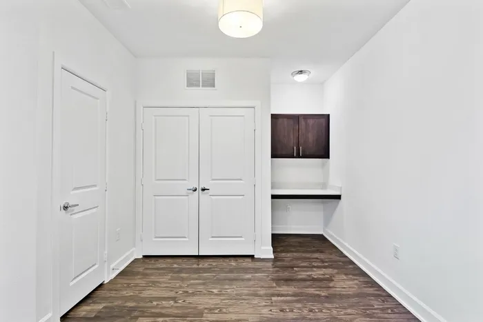 Spacious room with office space, dark wood-stained cabinets, vinyl plank flooring and closet access at Lantower Techridge apartments