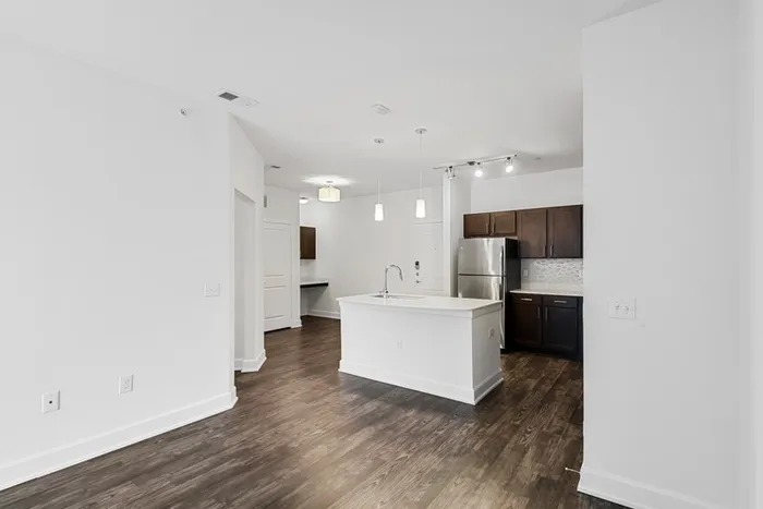 Spacious living and dining room with room for plenty of furniture, connected to Modern kitchen fit with diamond white quartz countertops and stainless steel sink basin, stainless steel appliances, and an island with overhead lighting at Lantower Techridge