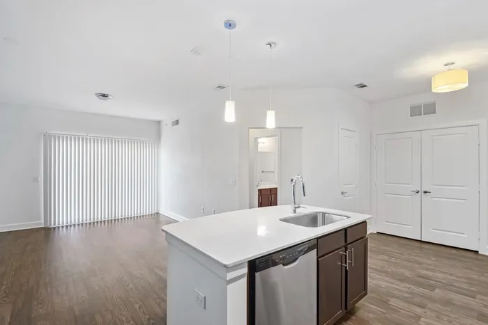 Spacious living and dining room with room for plenty of furniture, connected to Modern kitchen fit with diamond white quartz countertops and stainless steel sink basin, stainless steel appliances, and an island with overhead lighting at Lantower Techridge