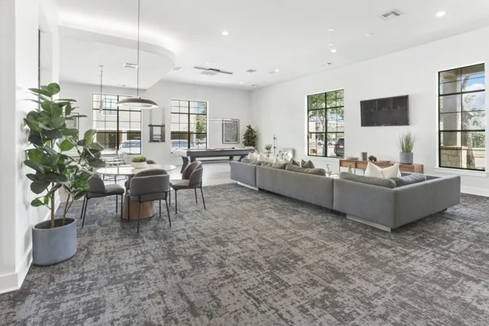 Modern lounging area with a wall mounted TV, cozy sofas, and dining tables at Lantower Residences at the Collection