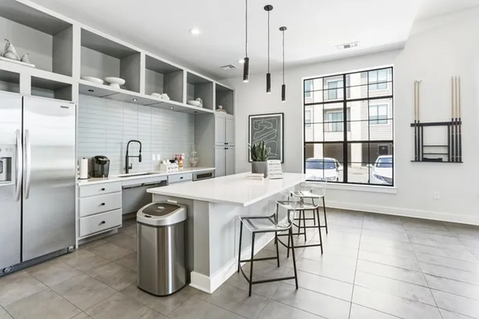 Modern kitchen fit with pristine white countertops, stainless steel appliances, and an island with overhead lighting and modern stools at Lantower Residences at the Collection