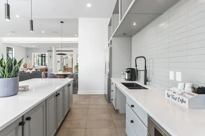 Modern kitchen fit with pristine white countertops, stainless steel appliances, and an island with overhead lighting and modern stools at Lantower Residences at the Collection