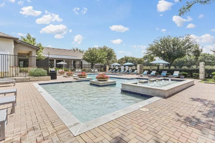 Resort-style swimming pool accented with flowers, has ample relaxing seating and umbrellas for shade and cooling at Lantower Residences at the Collection