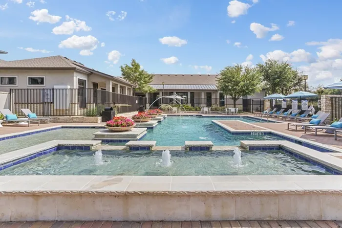 Resort-style swimming pool accented with flowers, has ample relaxing seating and umbrellas for shade and cooling at Lantower Residences at the Collection