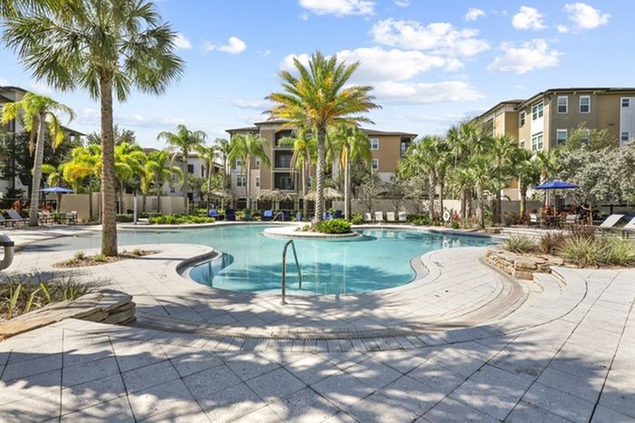 Resort-style pool with sundeck, palm trees, and lounge chairs at Lantower Brandon Crossroads