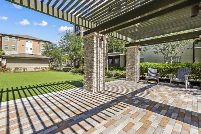 Shaded patio with lawn chairs and a large grassy area at Lantower Brandon Crossroads Apartments.