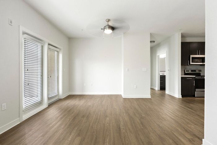 Living room with hardwood style-flooring and two large windows with natural sunlight at Lantower Brandon Crossroads.