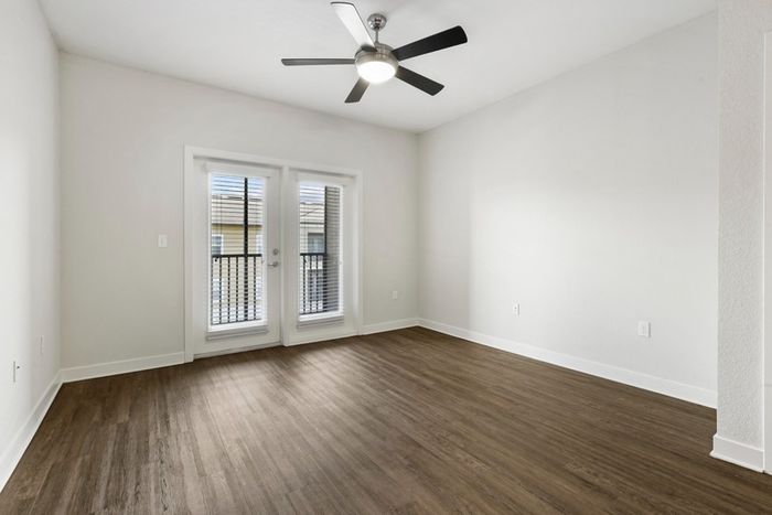 Living room with hardwood style-flooring and a glass door leading to the balcony at Lantower Brandon Crossroads.