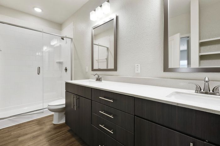 Modern, clean bathroom with dark-colored cabinetry, brushed nickel fixtures, and a walk-in, glass door shower at Lantower Brandon Crossroads.