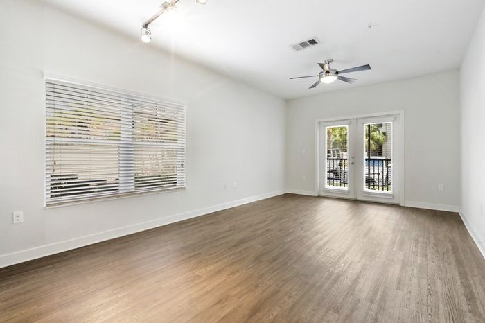 Spacious, naturally lit room with hardwood style-floors, two large windows, and glass doors leading to a balcony at Lantower Brandon Crossroads.