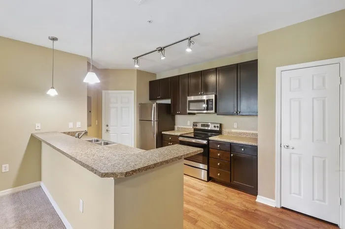 Image of a kitchen with black-on-silver appliances, a kitchen bar, 9-foor ceilings, and a wine rack at Lantower Cypress Creek.
