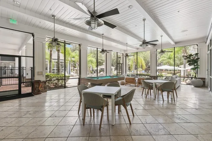 Image of Lantower Cypress Creek's clubhouse with a billiard table, TVs, Wi-Fi, ample seating, and floor-to-ceiling windows.