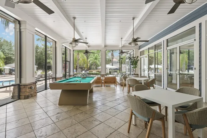 Image of Lantower Cypress Creek's clubhouse with a billiard table, TVs, Wi-Fi, ample seating, and floor-to-ceiling windows.