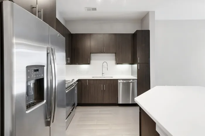 Kitchen at Bullhouse with wood-style flooring, stainless steel, energy efficient appliances, quarts countertops, a kitchen bar, and tile backsplash.