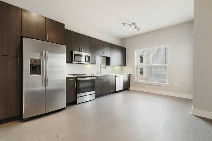 Spacious kitchen at Bullhouse with wood-style flooring, stainless steel, energy efficient appliances, quarts countertops, a large window, and tile backsplash.