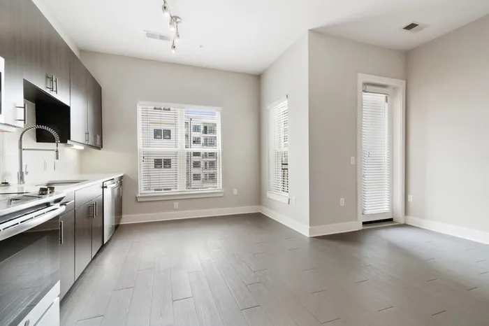 Spacious kitchen at Bullhouse with wood-style flooring, stainless steel, energy efficient appliances, quarts countertops, a large window, and tile backsplash.