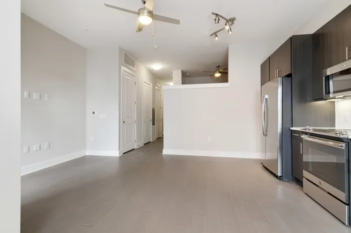Spacious kitchen at Bullhouse with wood-style flooring, stainless steel, energy efficient appliances, quarts countertops, 10-12-foot ceilings, and tile backsplash.