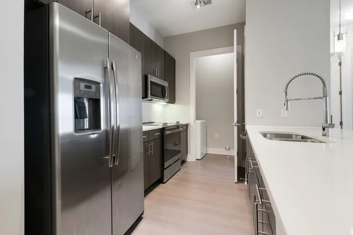 Spacious kitchen at Bullhouse with wood-style flooring, stainless steel, energy efficient appliances, quarts countertops, 10-12-foot ceilings, and tile backsplash.