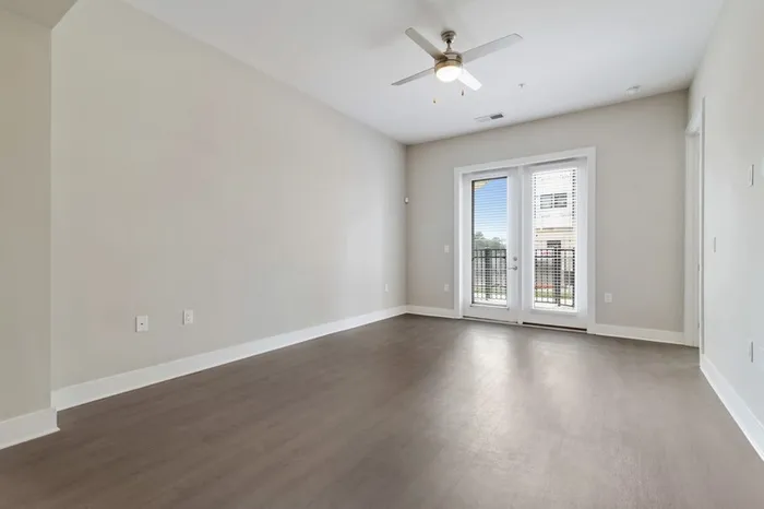 Living room with wood-style flooring, ceiling fan, and glass doors leading to a balcony at Bullhouse.