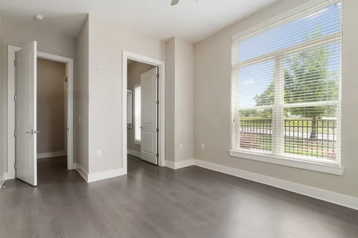 Bedroom with wood-style flooring, 10-12-foot ceilings, a walk-in closet, and a large window with ample natural sunlight at Lantower Bullhouse.