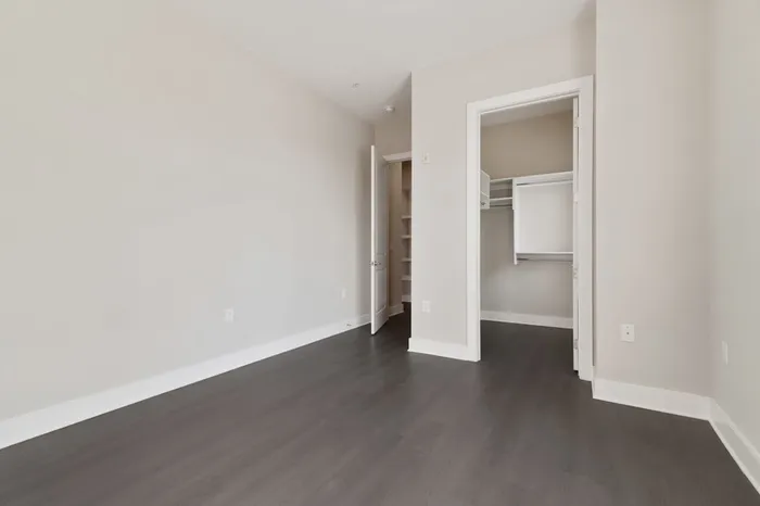 Bedroom with wood-style flooring, 10-12 foot ceilings, a walk in closet, and a large window with ample natural sunlight at Lantower Bullhouse.