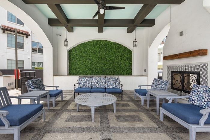 Outdoor lounge area with comfortable, padded seating, fireplace, and room for socialization at Lantower Ambrosio Apartments